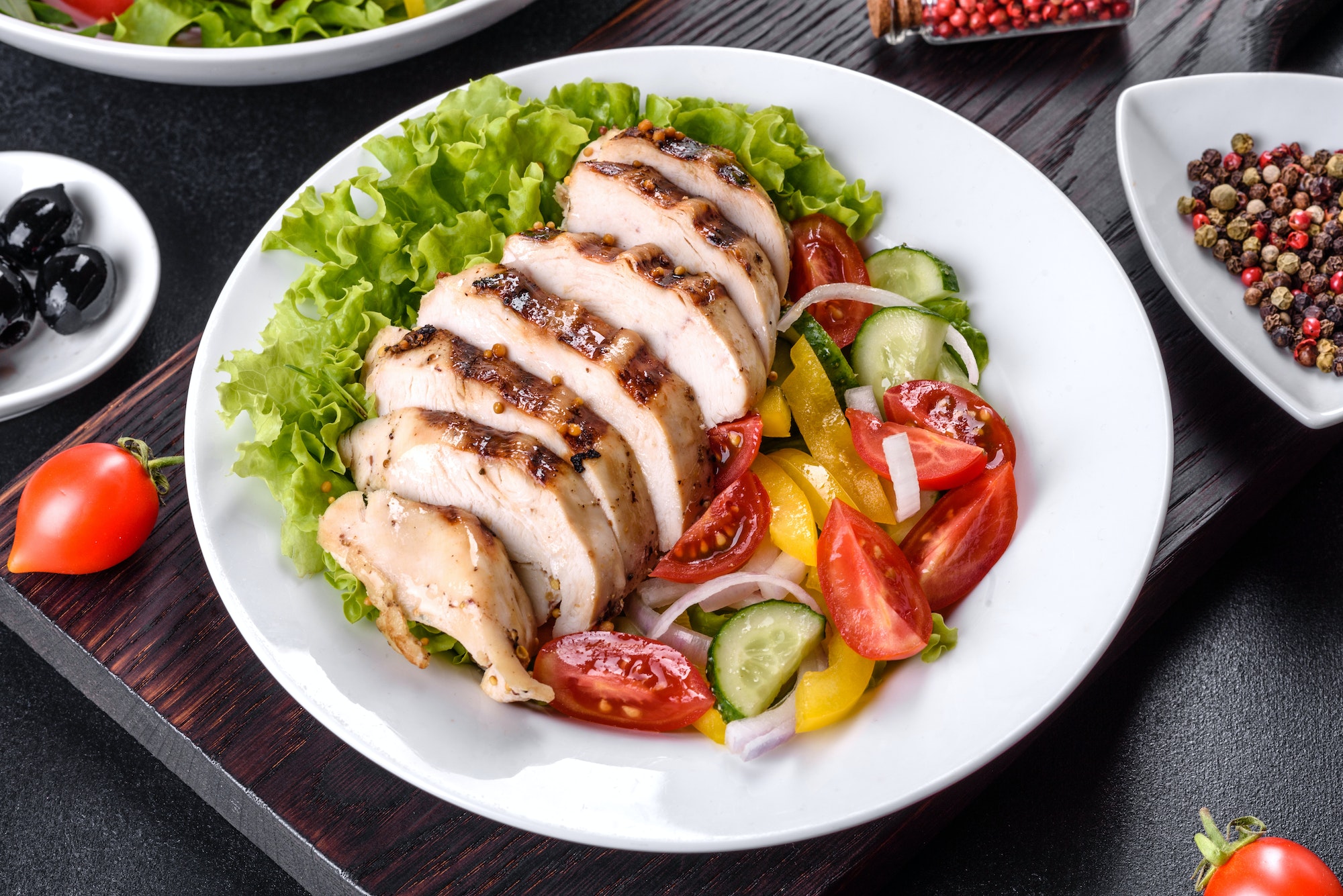 Three fresh delicious salads with chicken, tomato, cucumber, onions and greens with olive oil